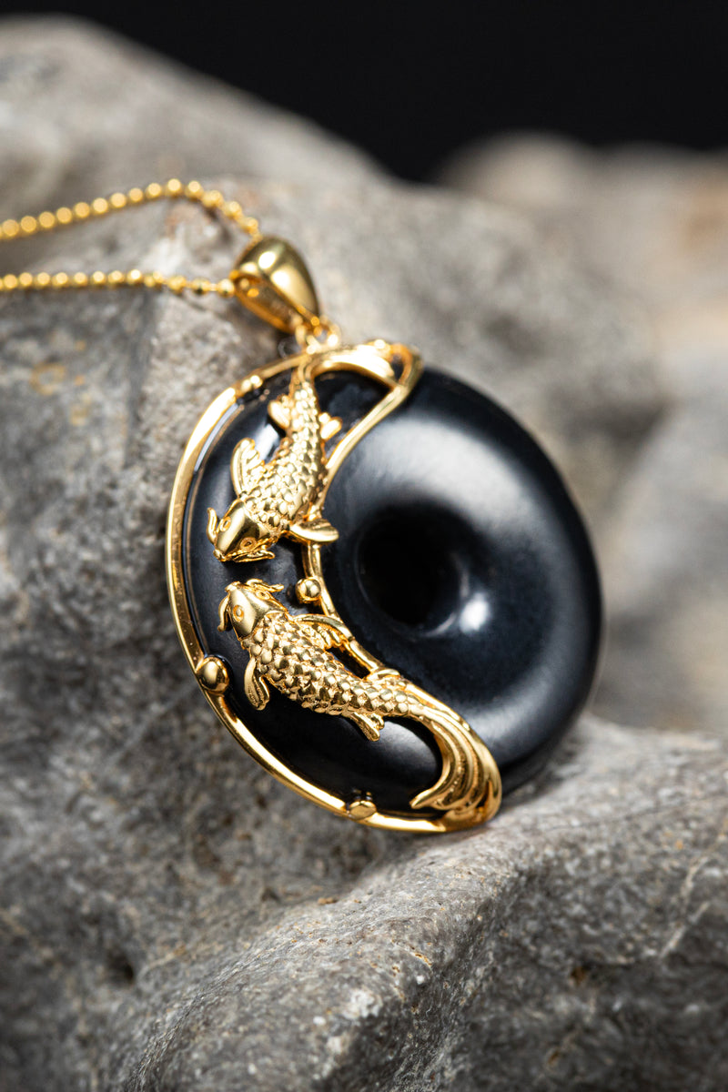 Two koi swimming up black jade, the old symbol of fortune that comes to those who keep going. Some people don't wait for luck. They wear it.